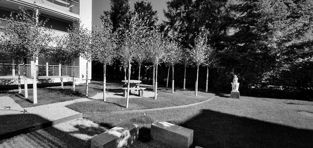 Garten mit Baumreihe, Steintisch und Skulptur