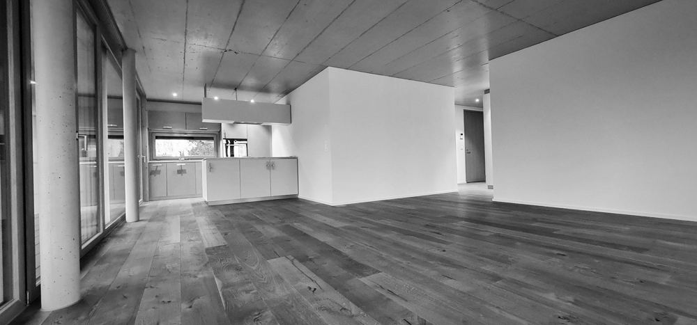 Offener Wohnraum mit Küche, Sichtbetondecke und Eichenparkett