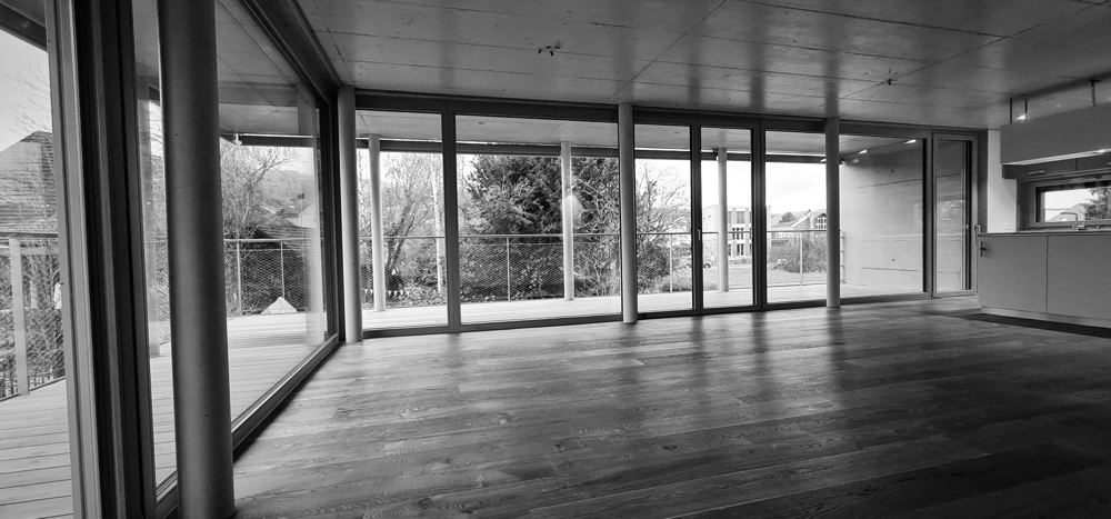 Wohnraum mit raumhohen Holz-Glas-Fronten und Eichenparkett