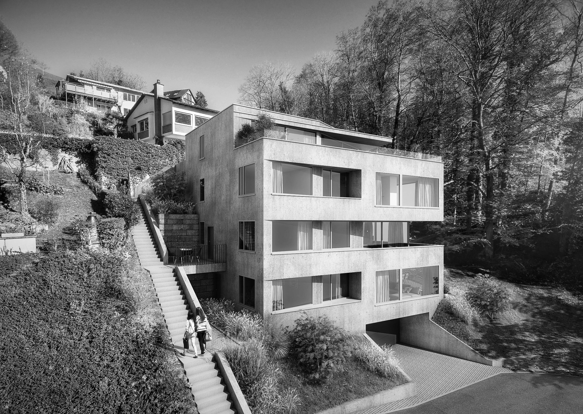 Mehrfamilienhaus aus Sichtbeton mit Holzfenstern am Hang, Treppe und Herbstwald
