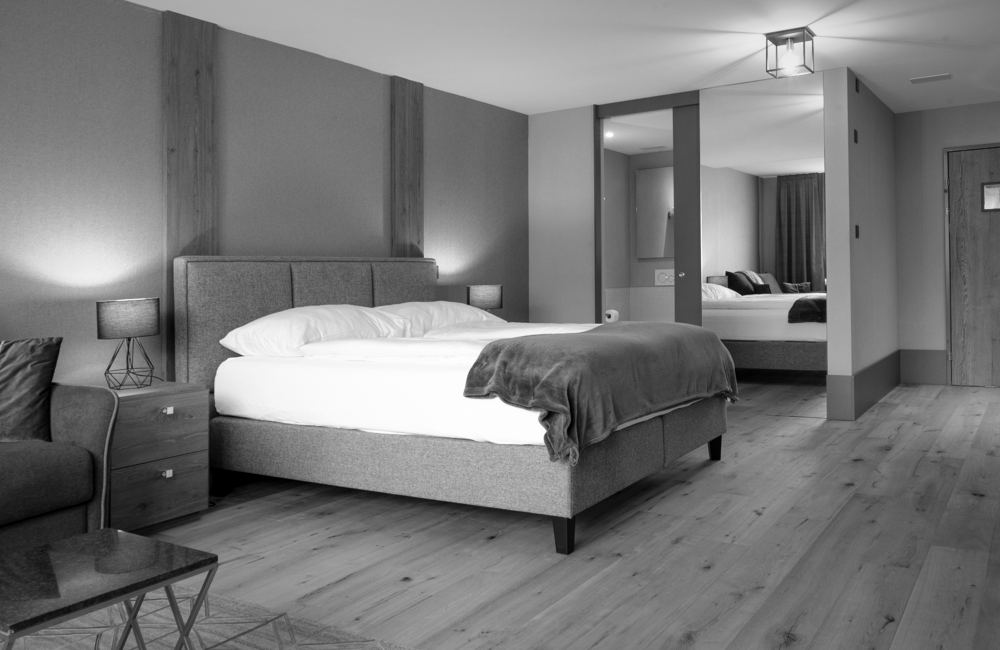 Hotelzimmer mit Boxspringbett, Holzpaneelen und Eichenparkett